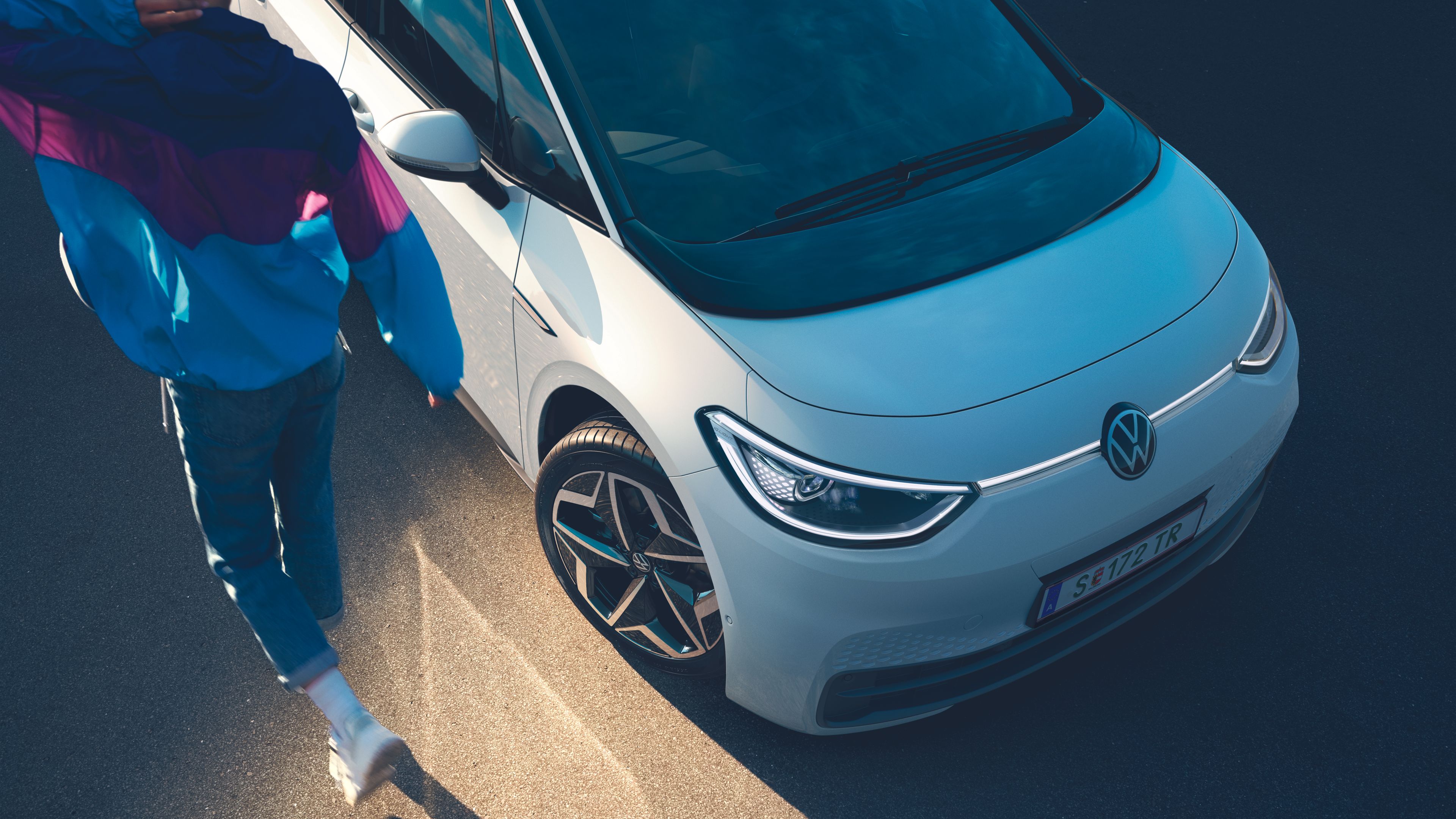 Blick von oben auf die Front des ID.3, ein Mann läuft neben dem Auto entlang