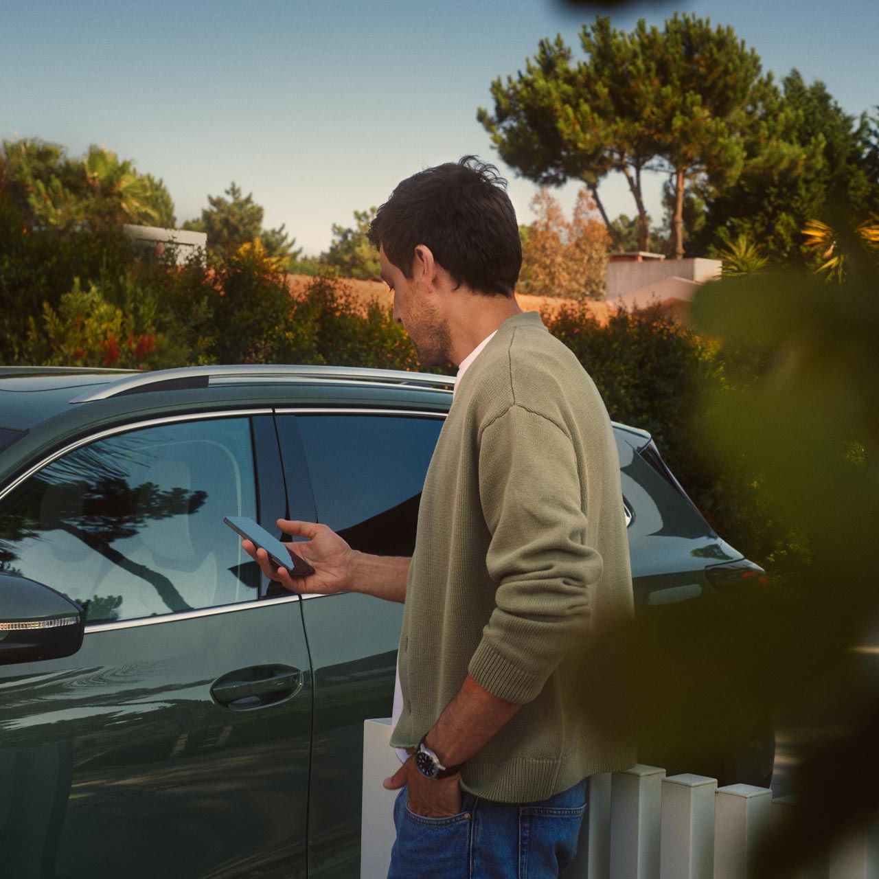 Mann bedient Park Assist des VW Tiguan auf seinem Smartphone