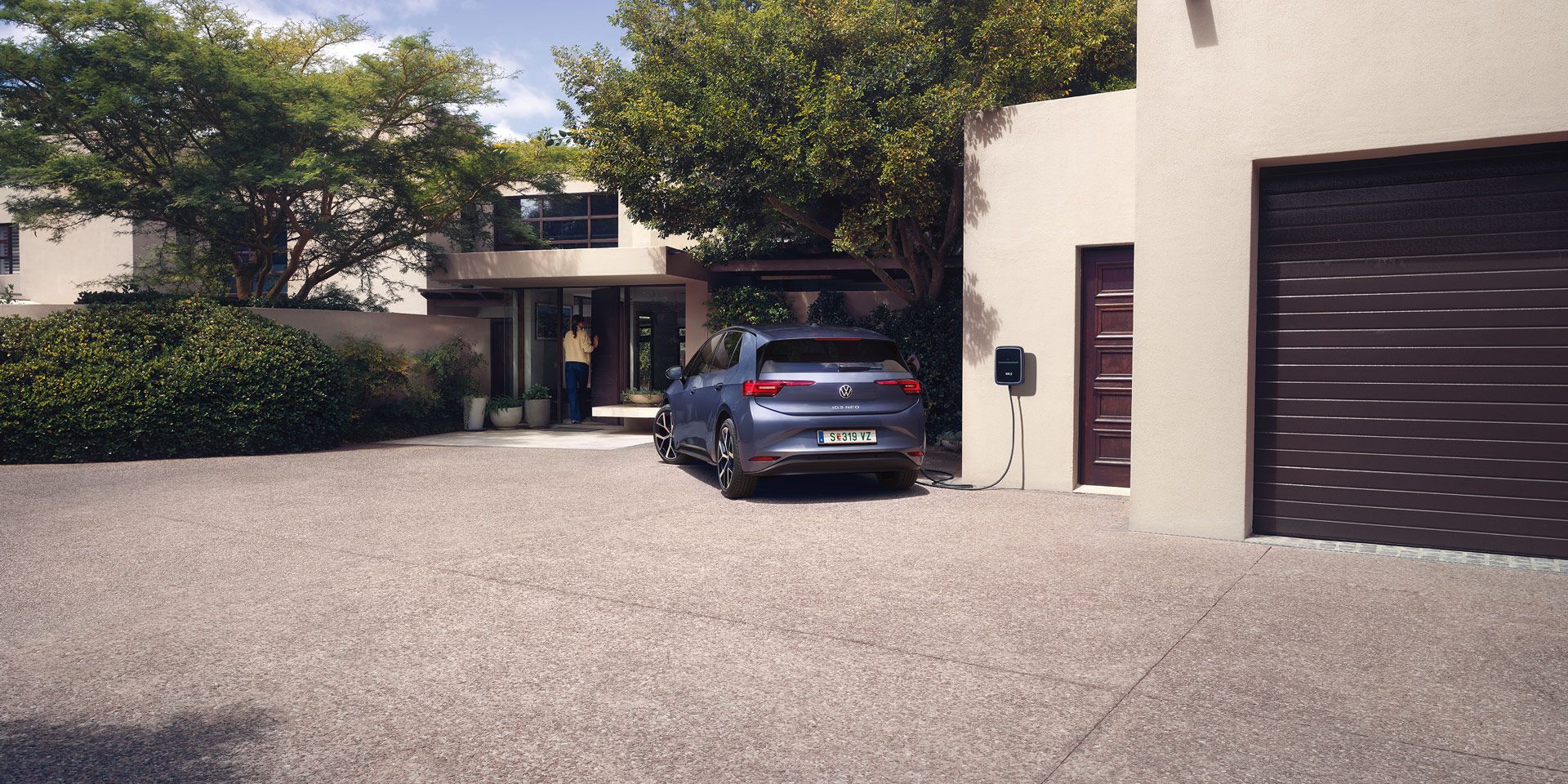 Ein blauer VW ID.3 Neo lädt an einer Wallbox vor einem Einfamilienhaus