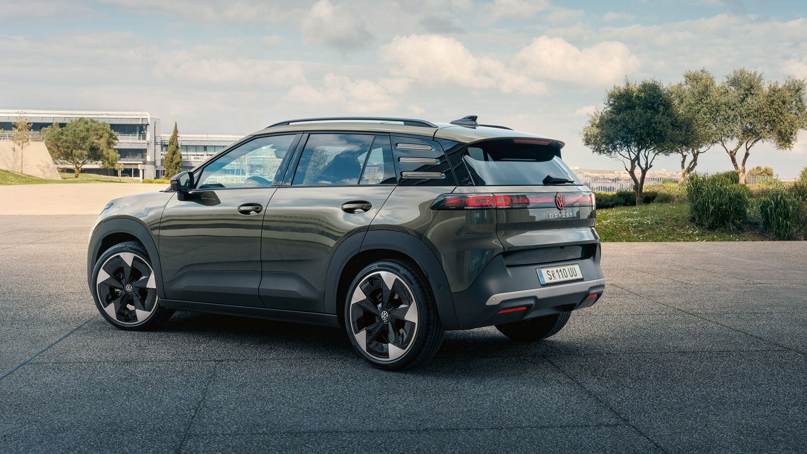 Heckansicht eines grünen VW ID. Cross, der auf einem Platz mit grünen Bäumen parkt.