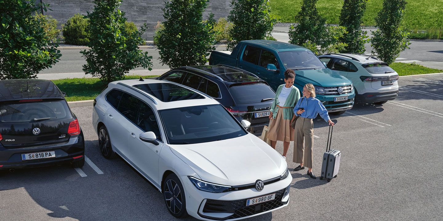 Zwei Frauen stehen auf einem Parkplatz neben einem weißen VW Passat B9