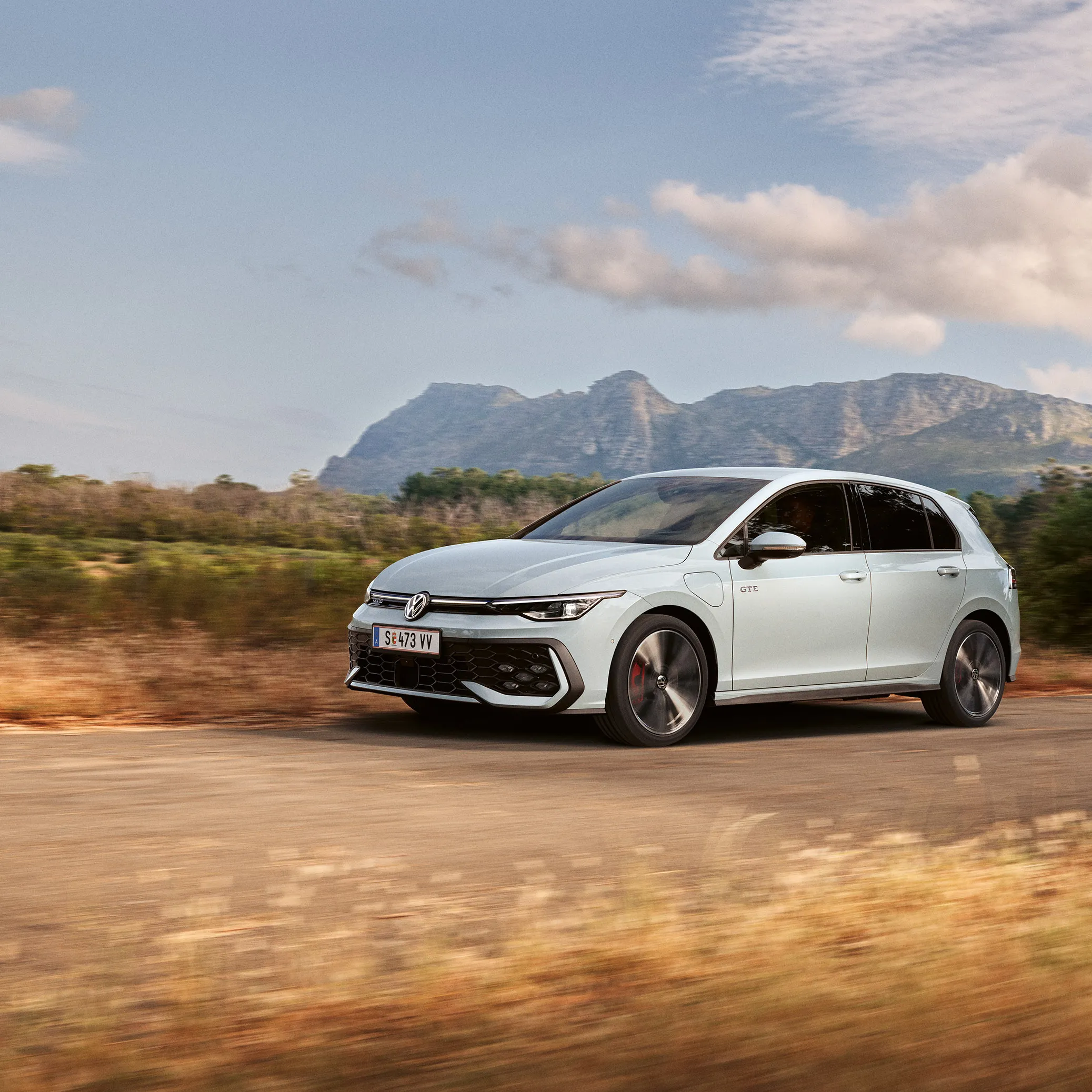 Der VW Golf GTE fährt auf einer Landstraße, im Hintergrund sieht man Berge