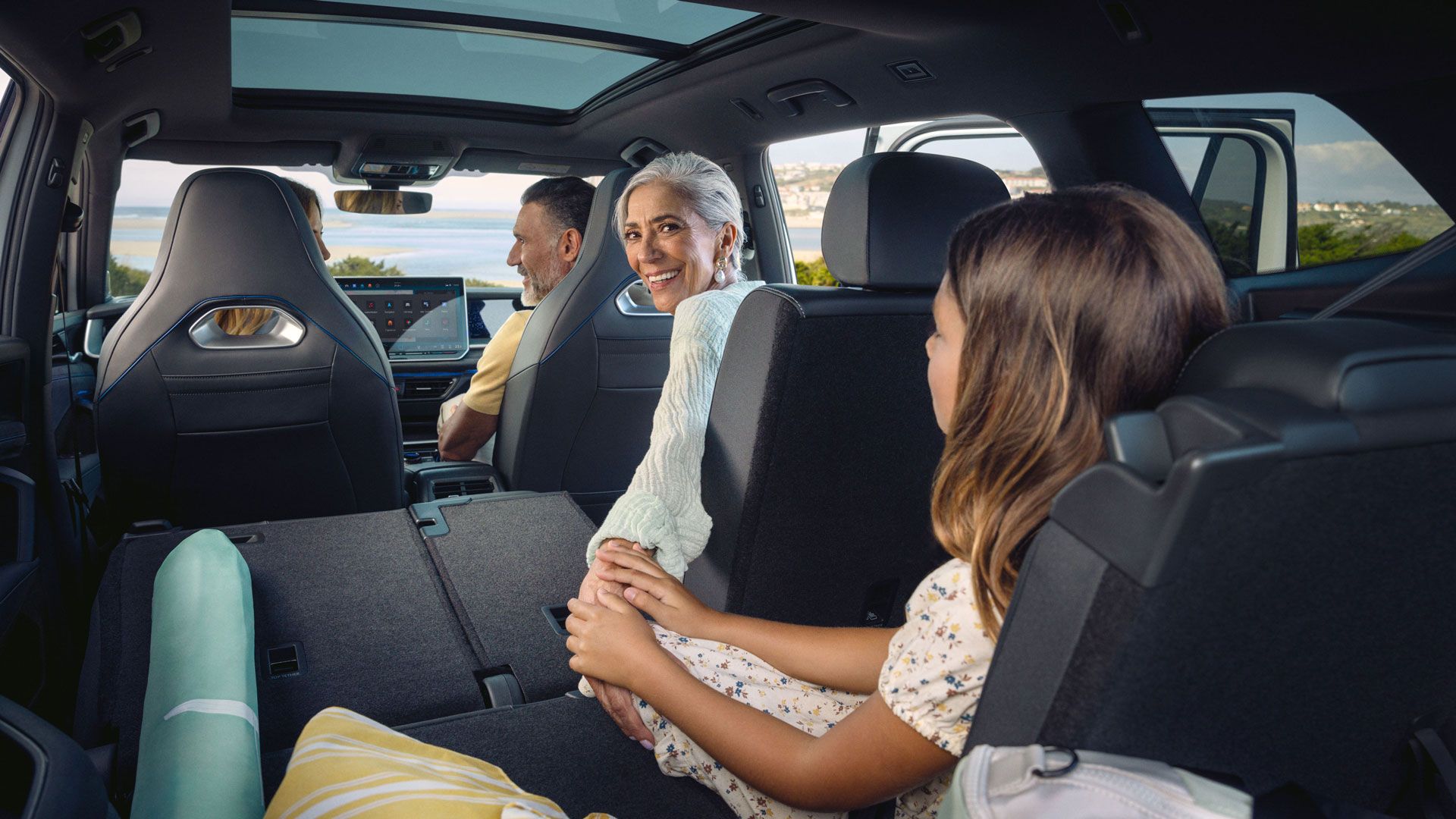Eine Familie sitzt auf drei Sitzreihen verteil im VW Tayron, die Sitze sind teilweise zu einer großen Ladefläche umgeklappt.