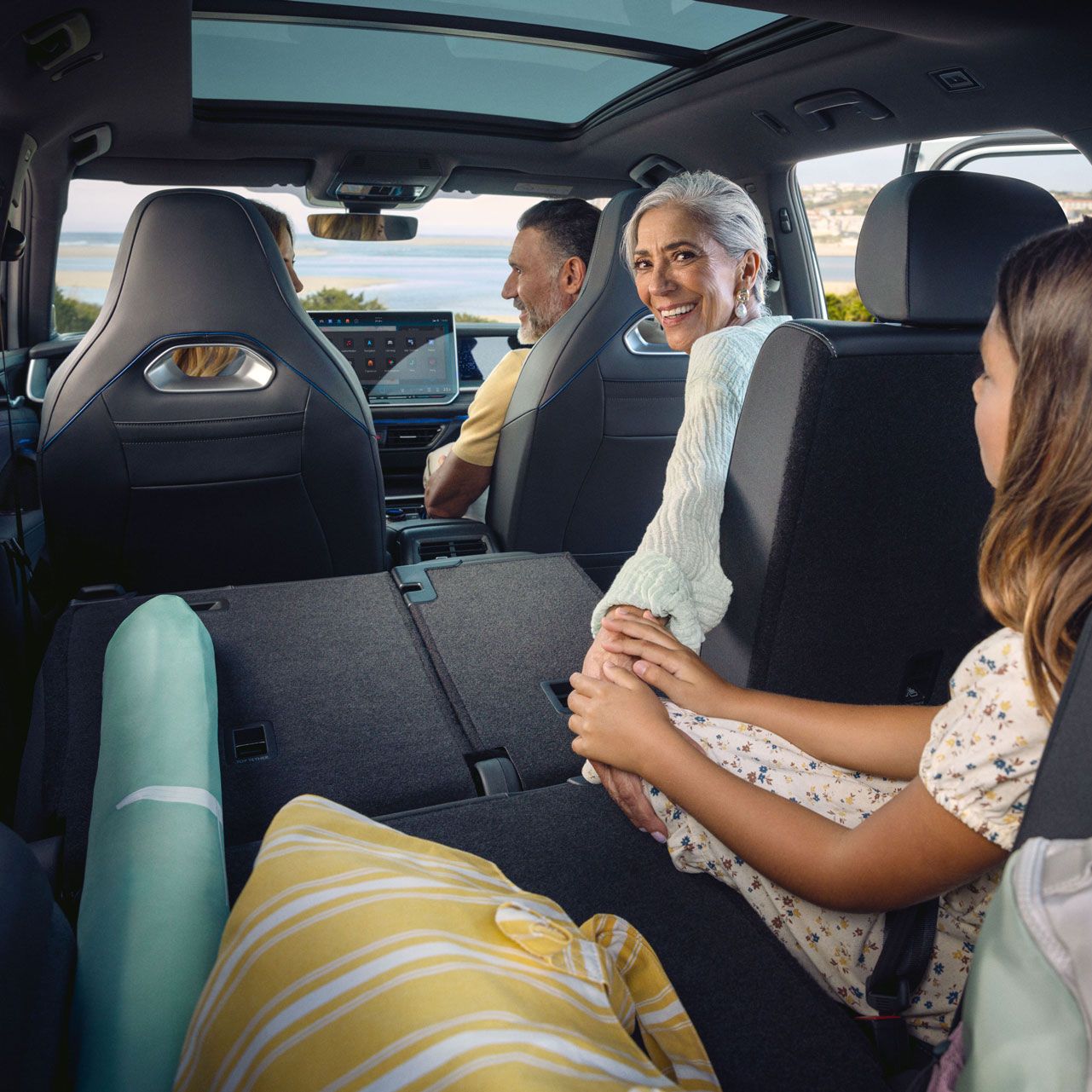 Eine Familie sitzt auf drei Sitzreihen verteil im VW Tayron, die Sitze sind teilweise zu einer großen Ladefläche umgeklappt.