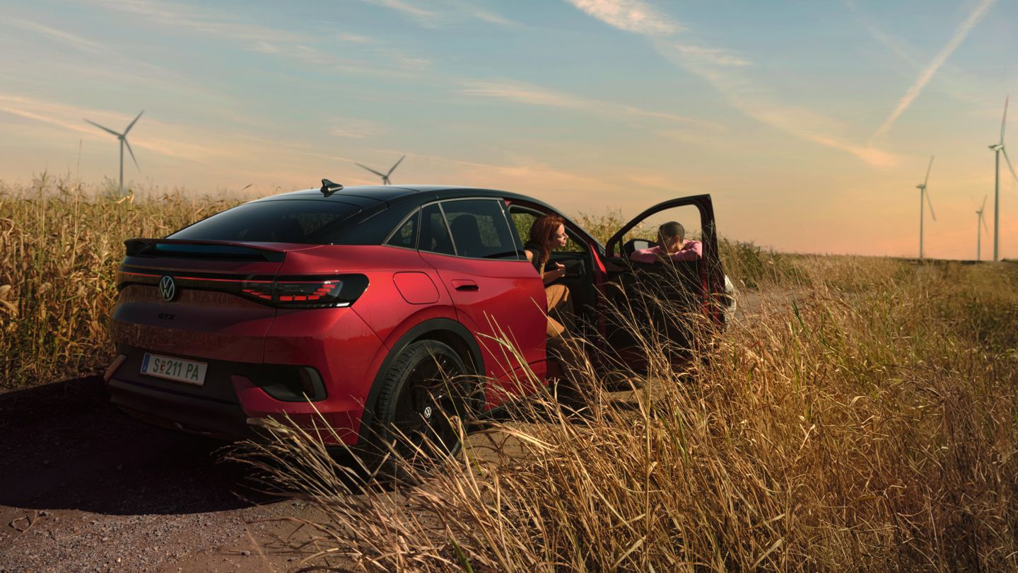 Zwei Personen unterhalten sich neben einem roten ID.5 GTX auf einer Landstraße