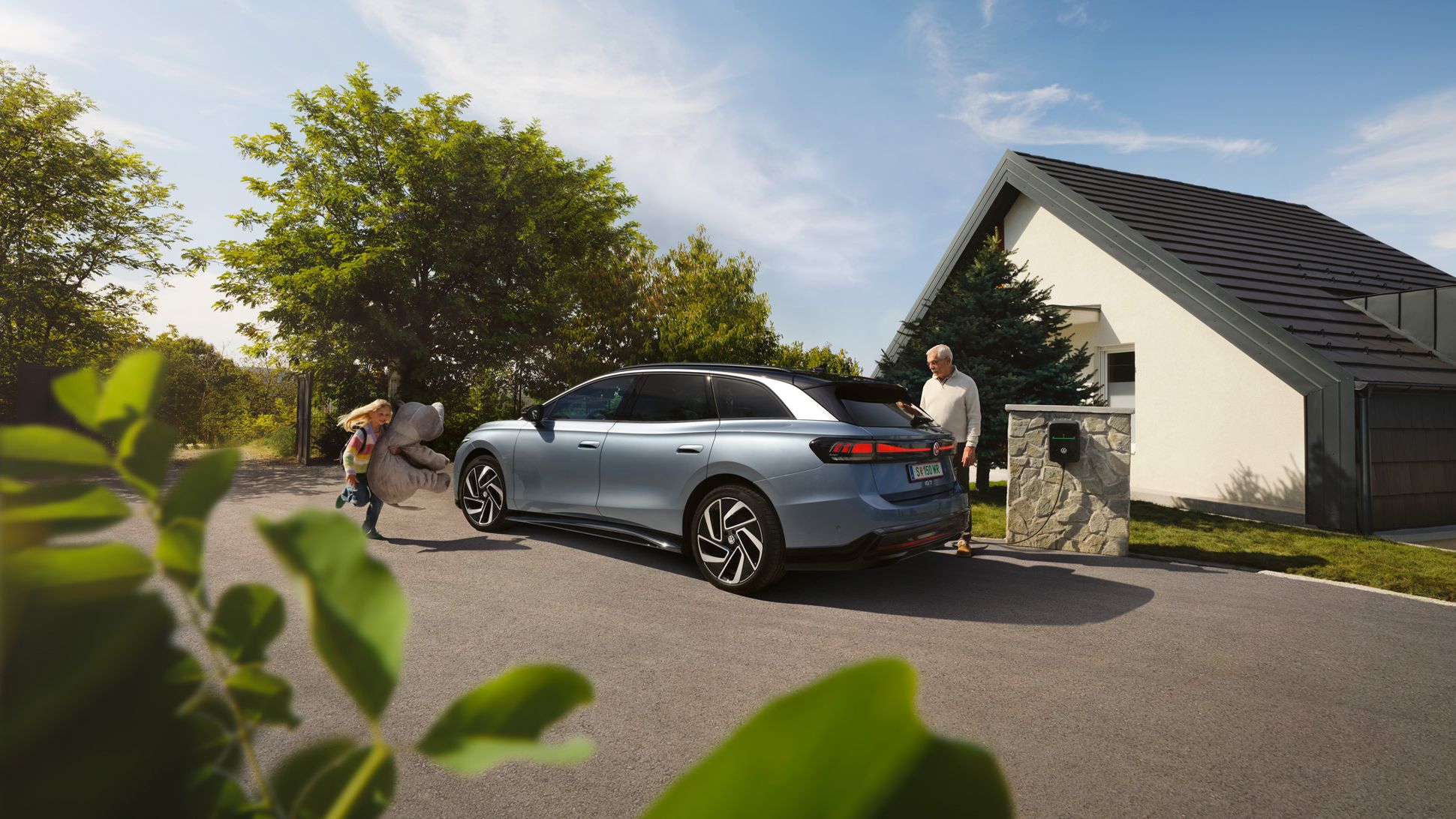 Ein VW ID.7 Tourer parkt vor einem Haus und wird am ID. Charger 2 geladen.