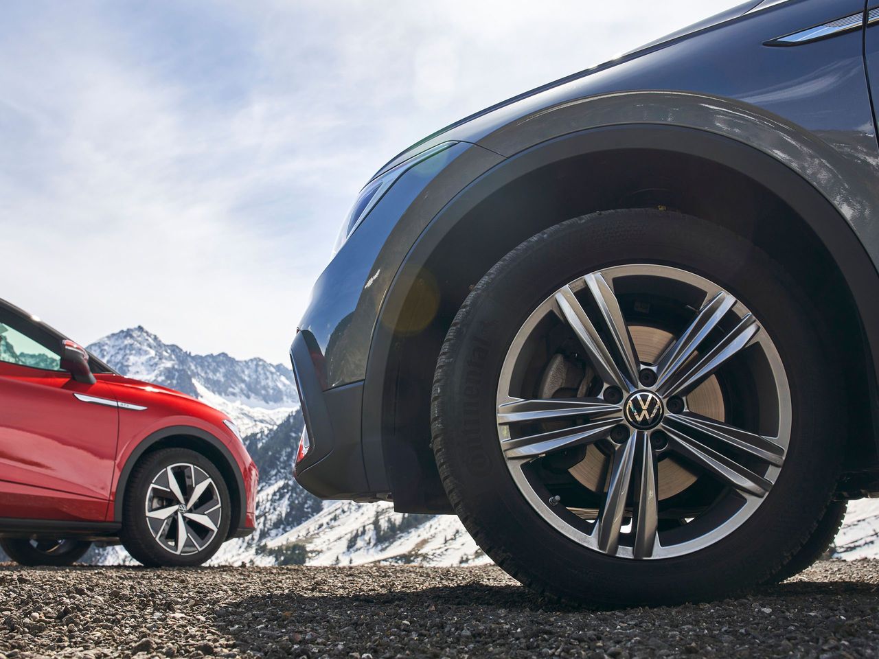 Nahaufnahme von Volkswagen Winterkompletträdern an einem blauen und an einem roten Volkswagen.