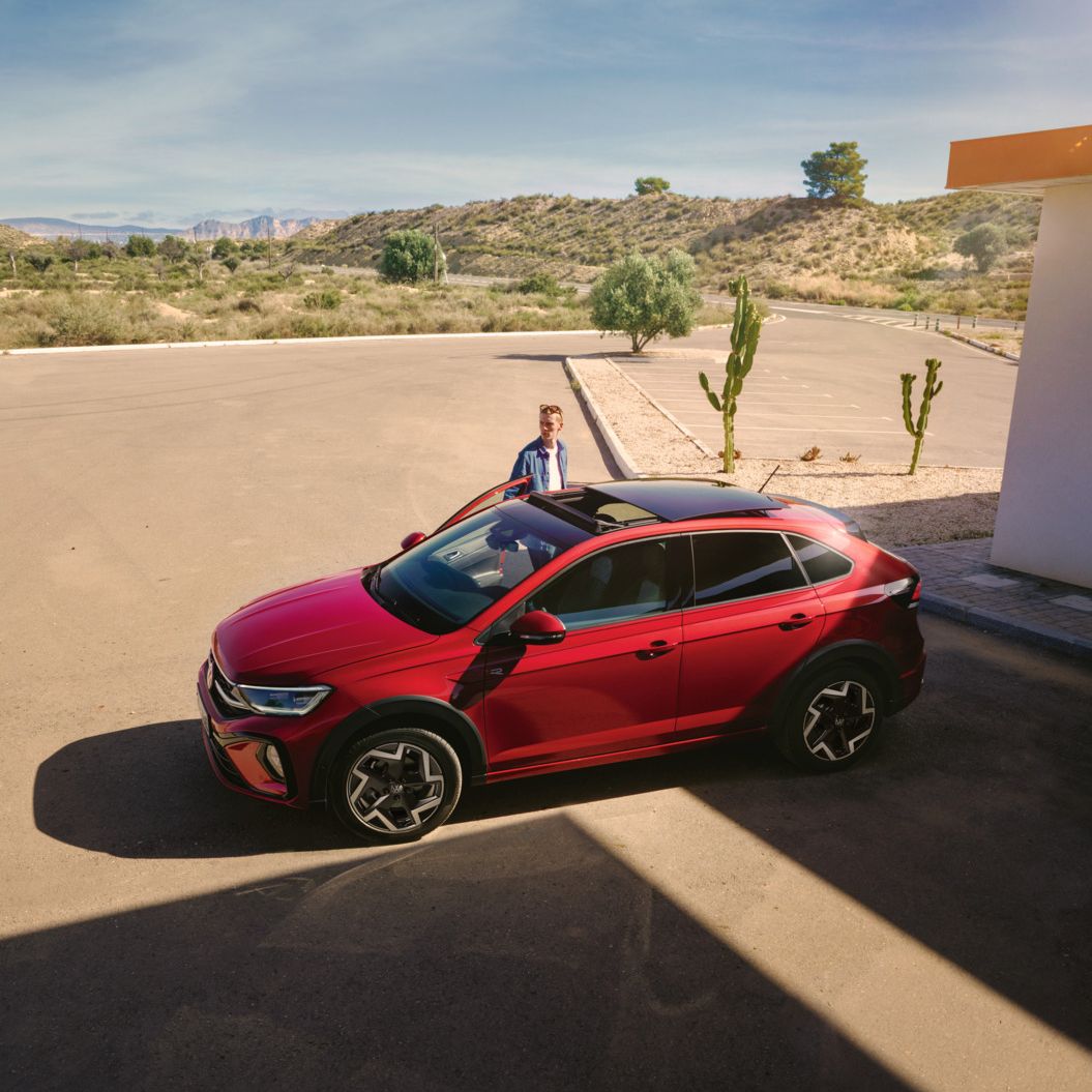 Seitenansicht eines roten VW Taigo R-Line, Mann öffnet Beifahrertür
