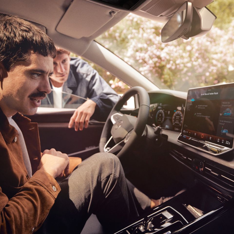 Zwei junge Männer nutzen den Sprachassistenten im VW Golf.