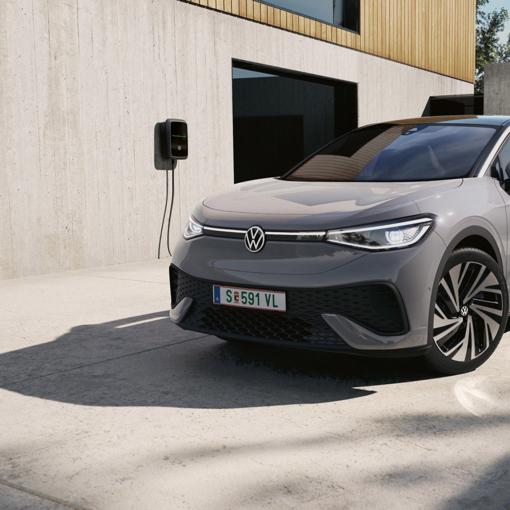 Ein grauer VW ID.5 schräg von vorne, der an einer VW Wallbox geladen wird.