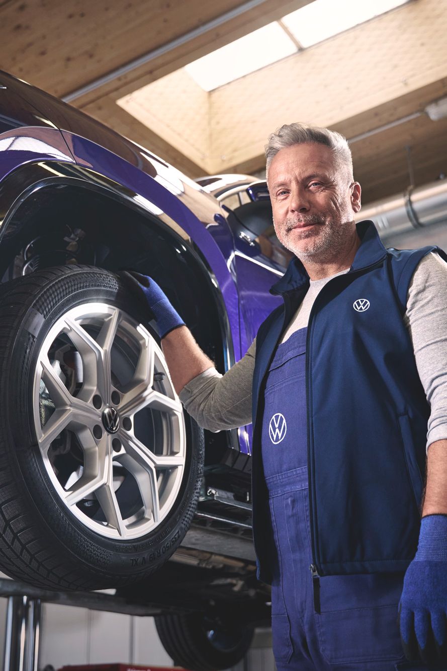 Ein Volkswagen Mechaniker wechselt die Räder bei einem Volkswagen Tayron.