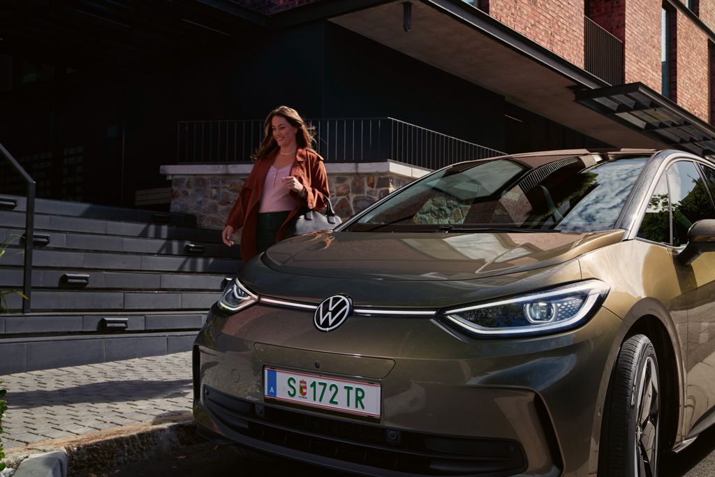 Der VW ID.3 in Olivgrün von vorne, hinter ihm geht eine Frau