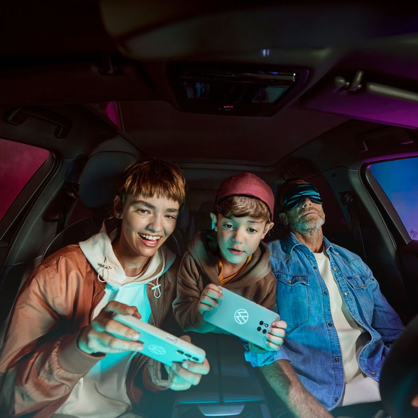Vater mit zwei Kindern im Volkswagen, die Kinder spielen mit der AirConsole.