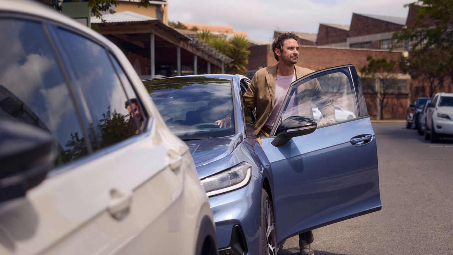 Ein Mann steigt am Straßenrand aus einem parkenden blauen VW ID.3 Neo