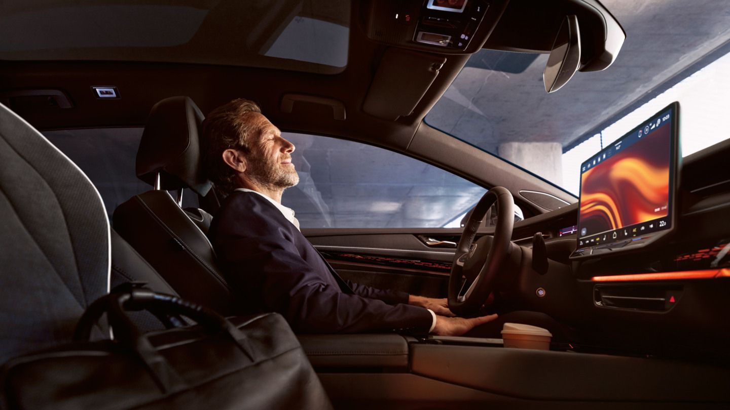 Ein Mann sitzt entspannt im VW ID.7, sichtbar sind Lenkrad und Infotainment-Display.