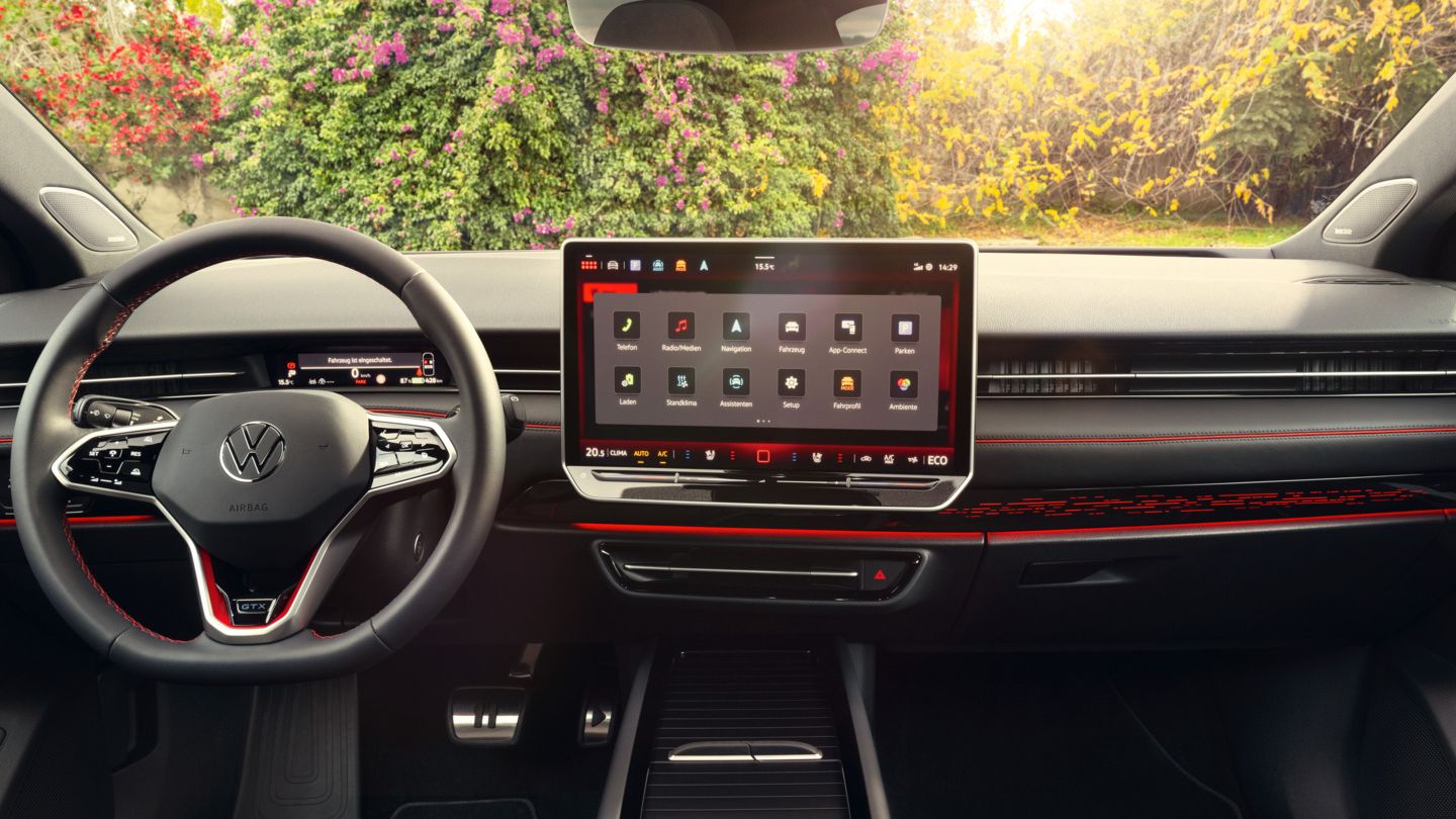 Cockpit eines VW ID.7 GTX mit Multifunktionslenkrad und Infotainmentsystem mit roten Akzenten.