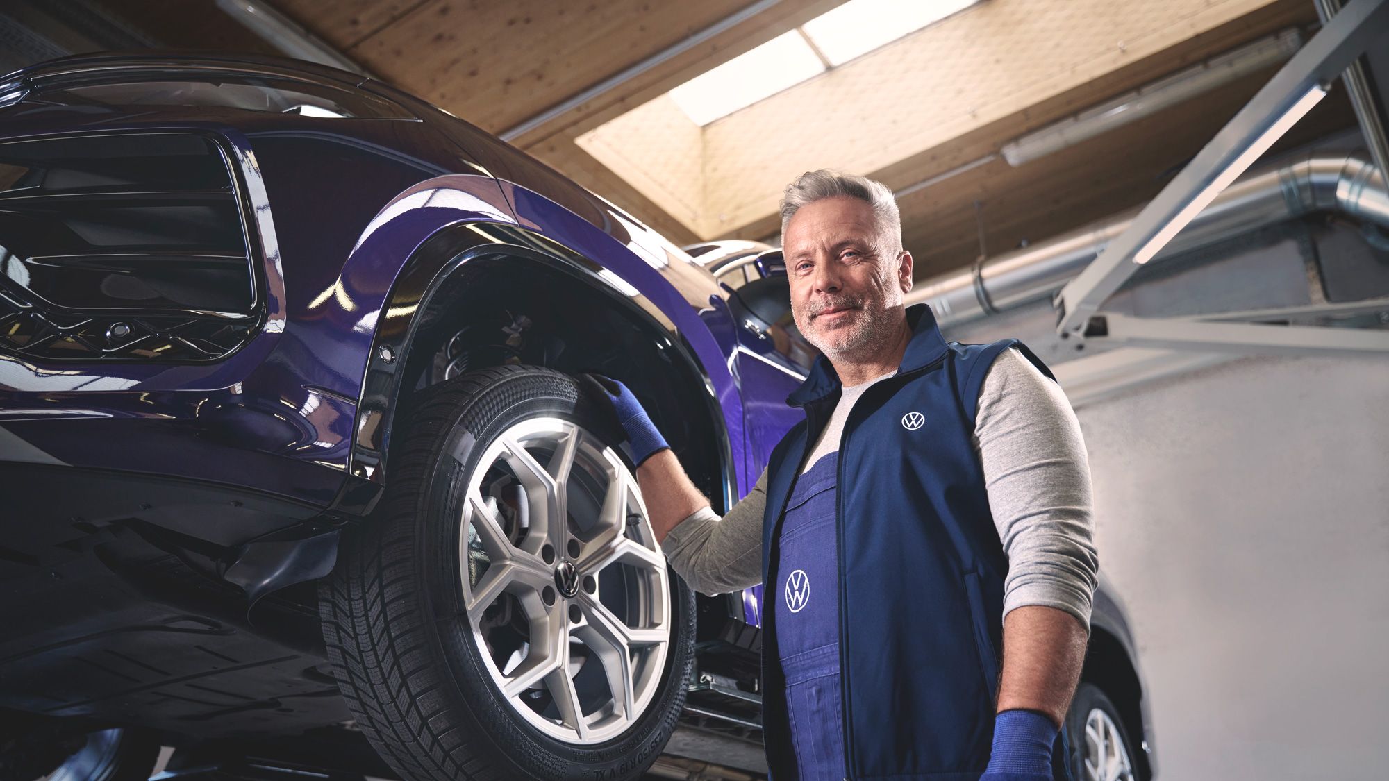 Ein Volkswagen Mechaniker wechselt die Räder bei einem Volkswagen Tayron.