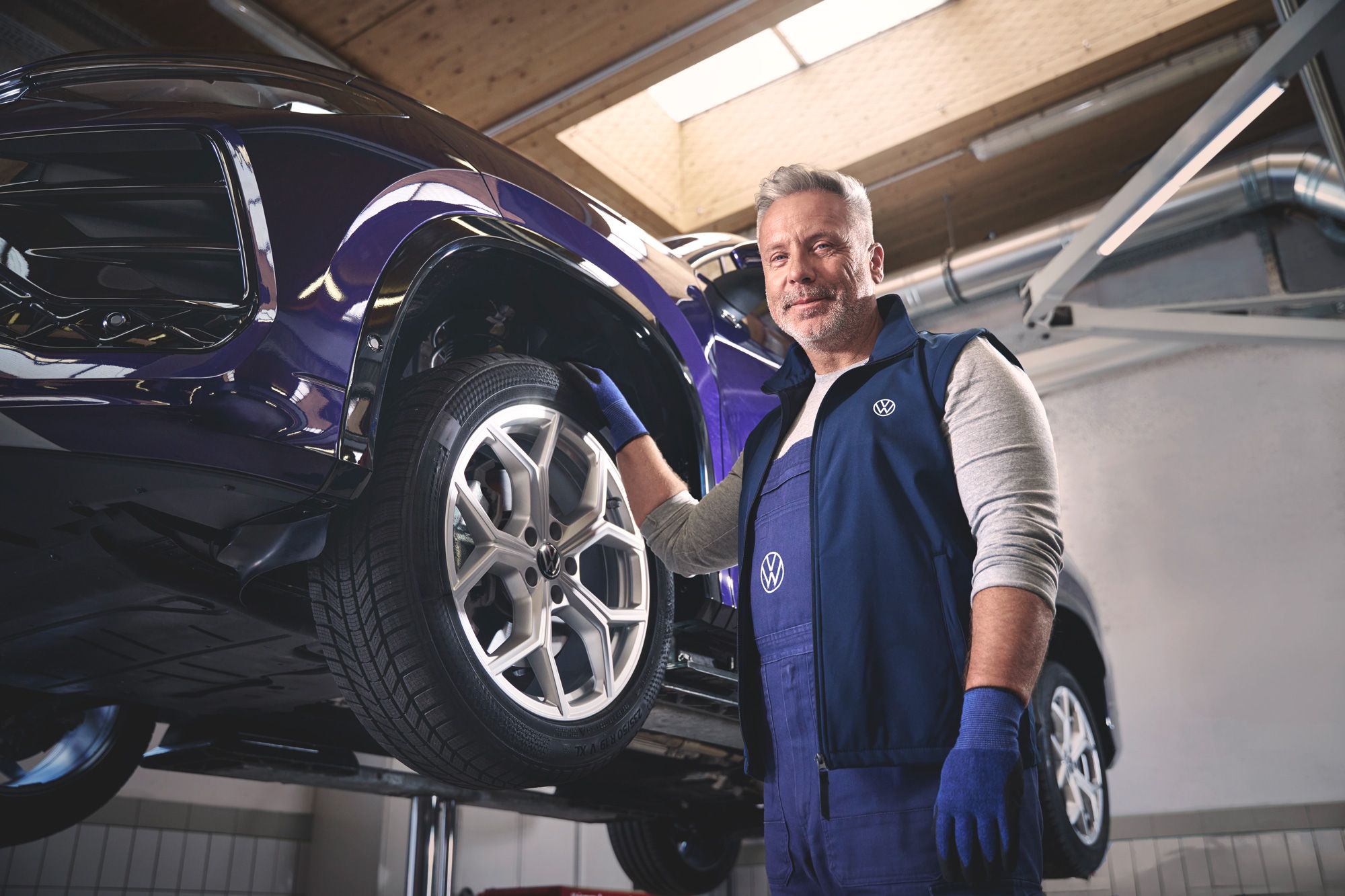 Ein Volkswagen Mechaniker wechselt die Räder bei einem Volkswagen Tayron.