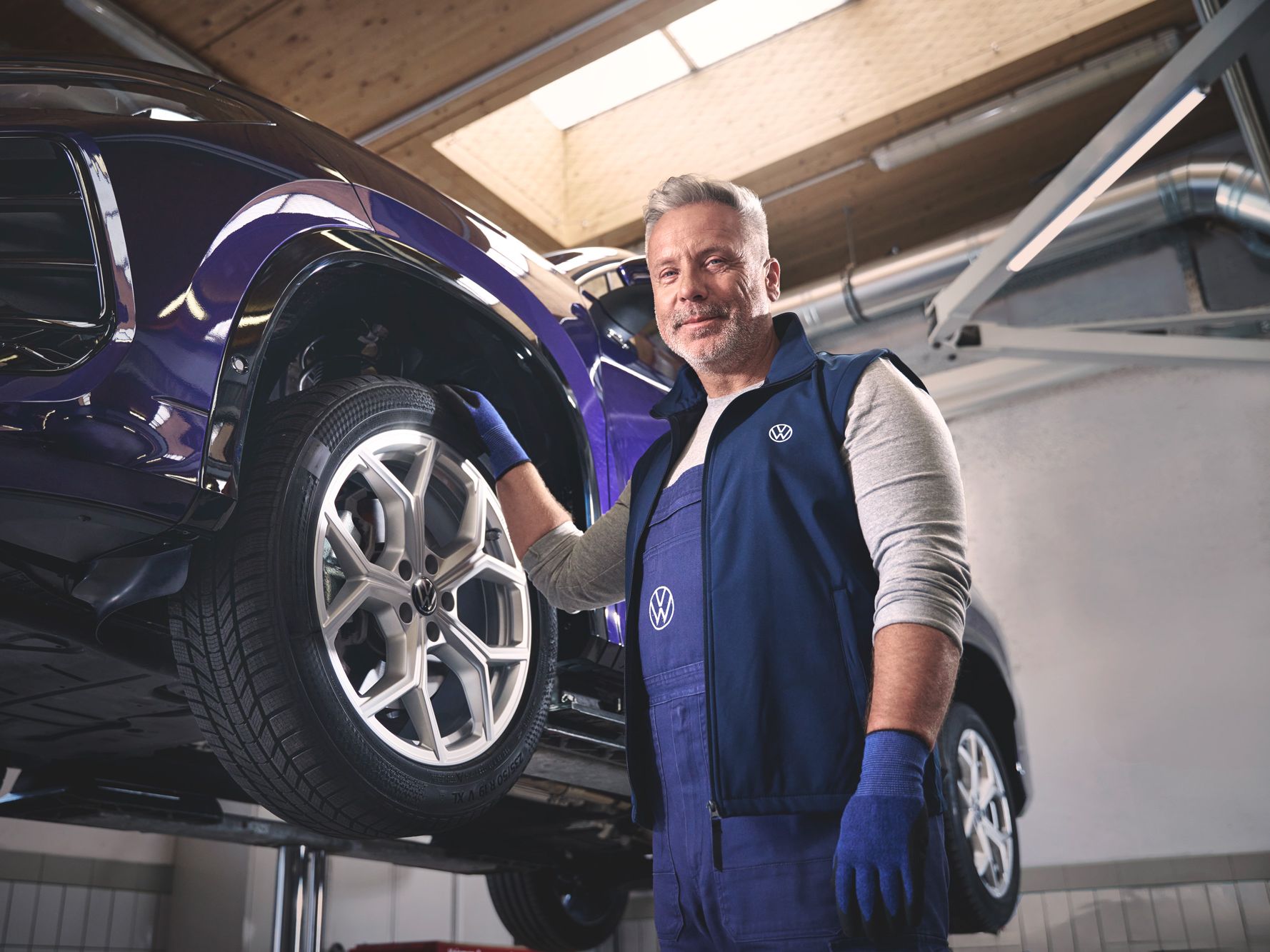 Ein Volkswagen Mechaniker wechselt die Räder bei einem Volkswagen Tayron.