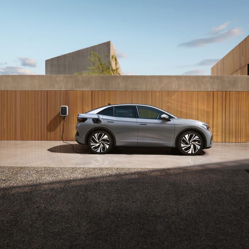 Seitenansicht eines grauen VW ID.5, der an einer Wallbox aufgeladen wird. 