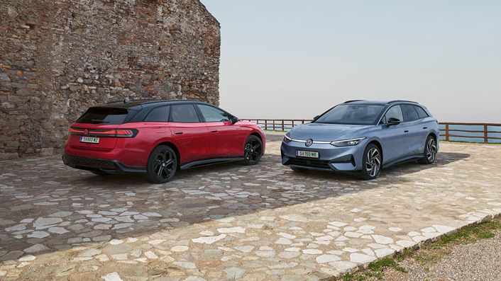 Ein roter VW ID.7 GTX Tourer und ein blauer VW ID.7 Tourer stehen auf einer Parkfläche am Meer.