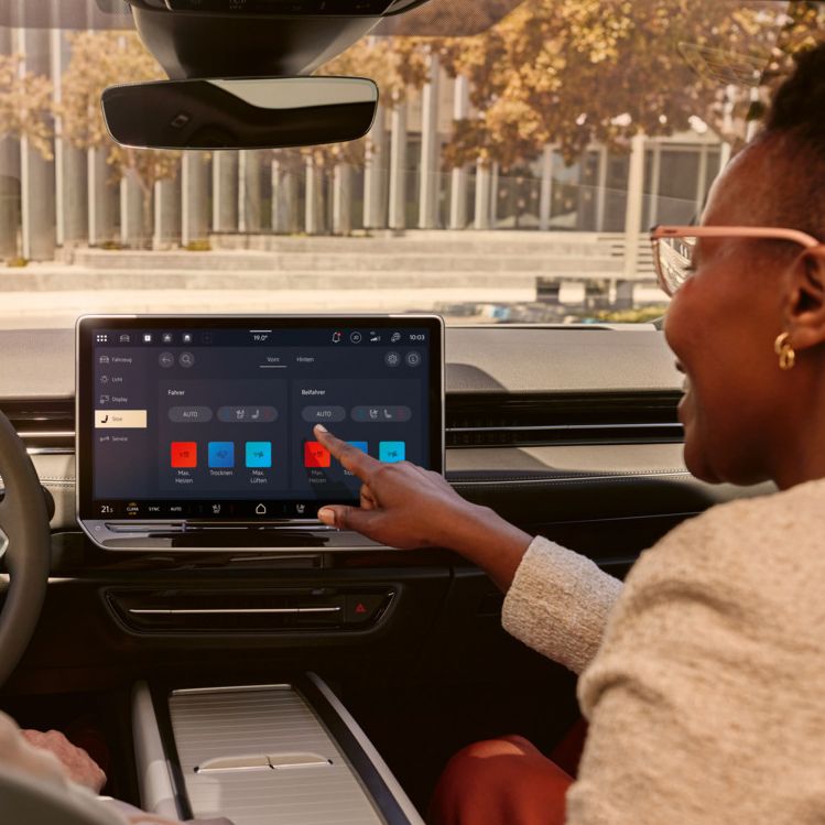 Zwei Frauen, die lachen, sitzen auf den Vordersitzen im VW ID.7 und bedienen das Infotainment-System.