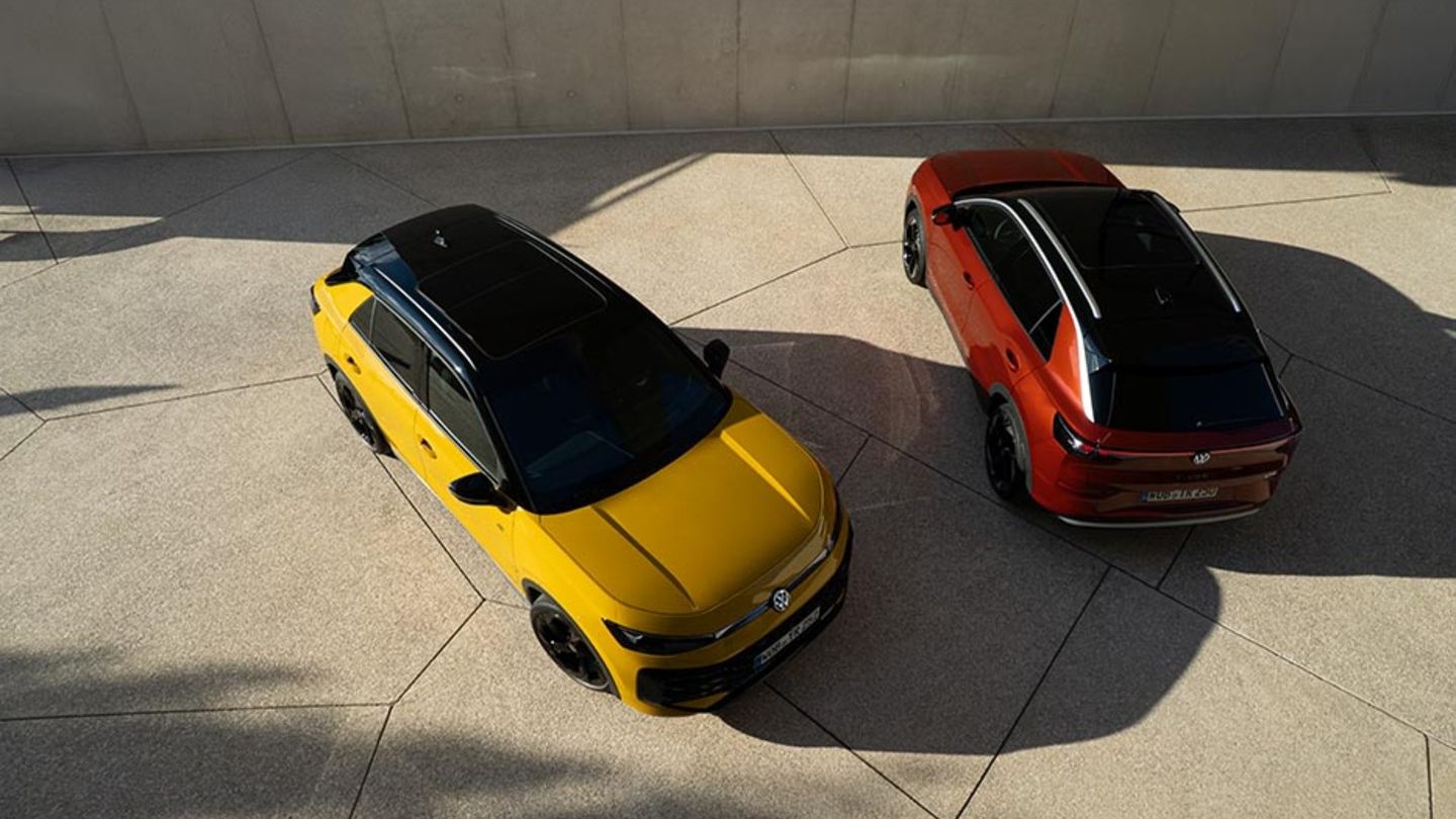 Ein gelber VW T-Roc R-Line und ein roter VW T-Roc Style von schräg oben vor einem modernen Gebäude.