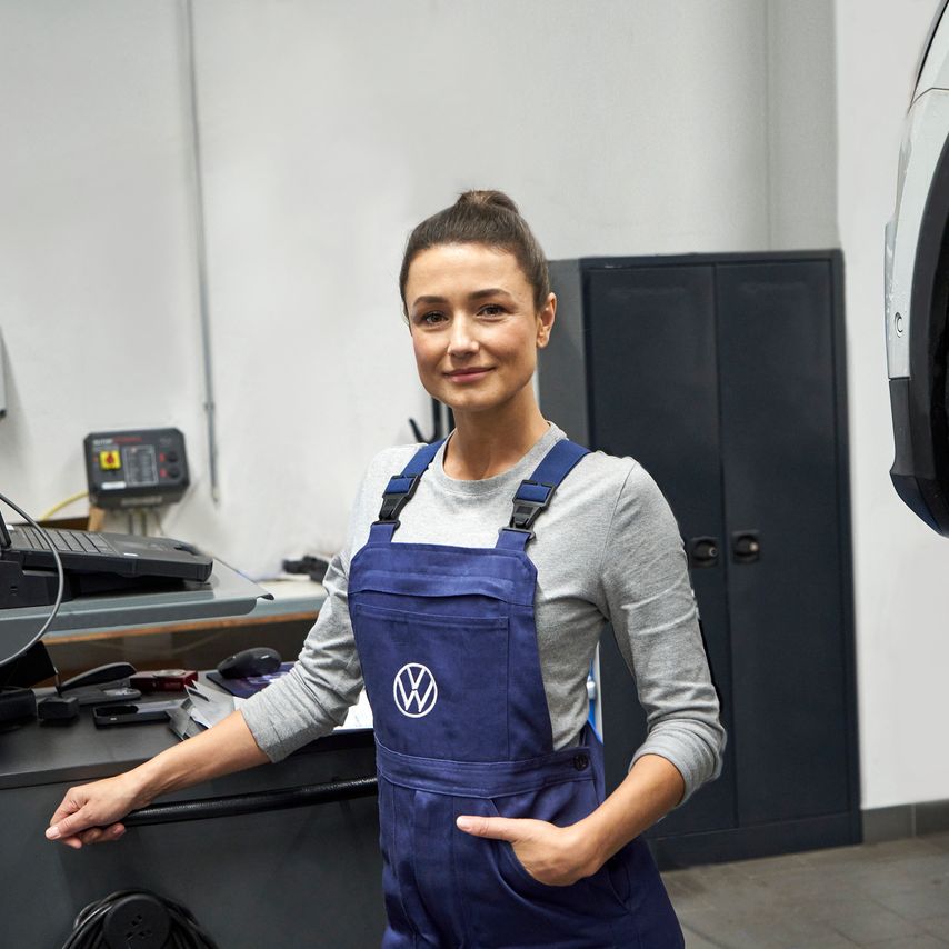 Eine Volkswagen Service Technikerin neben einem Pult mit technischer Ausrüstung