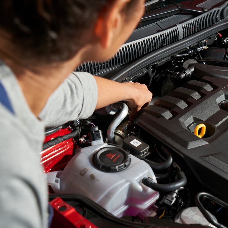Ein VW Service Techniker wechselt die Glühkerzen bei einem Volkswagen