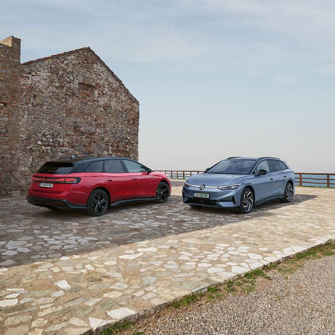 Ein roter VW ID.7 GTX Tourer und ein blauer VW ID.7 Tourer stehen auf einer Parkfläche am Meer.