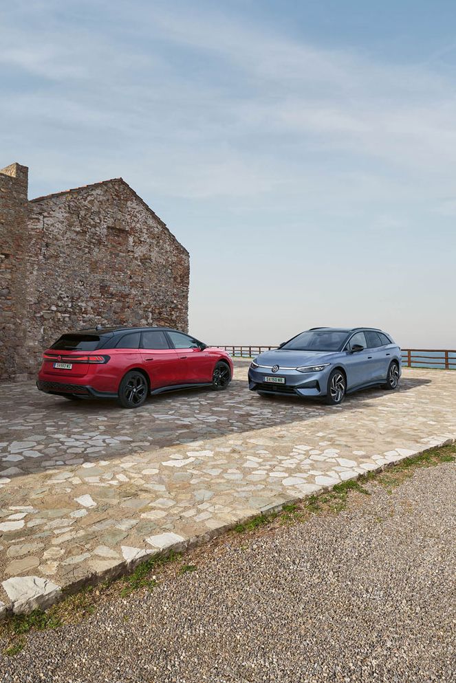 Ein roter VW ID.7 GTX Tourer und ein blauer VW ID.7 Tourer stehen auf einer Parkfläche am Meer.
