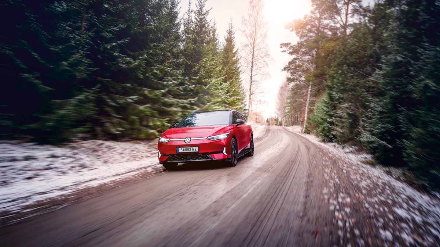 Ein roter VW ID.7 GTX Tourer fährt auf einem Waldweg, auf dem Boden liegt Schnee.