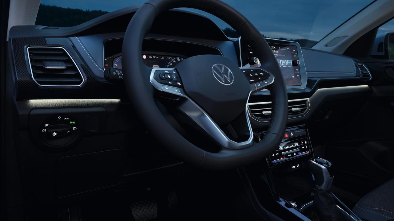 Cockpit eines VW T-Cross in der Dämmerung mit Multifunktionslenkrad und weißer Ambientebeleuchtung.