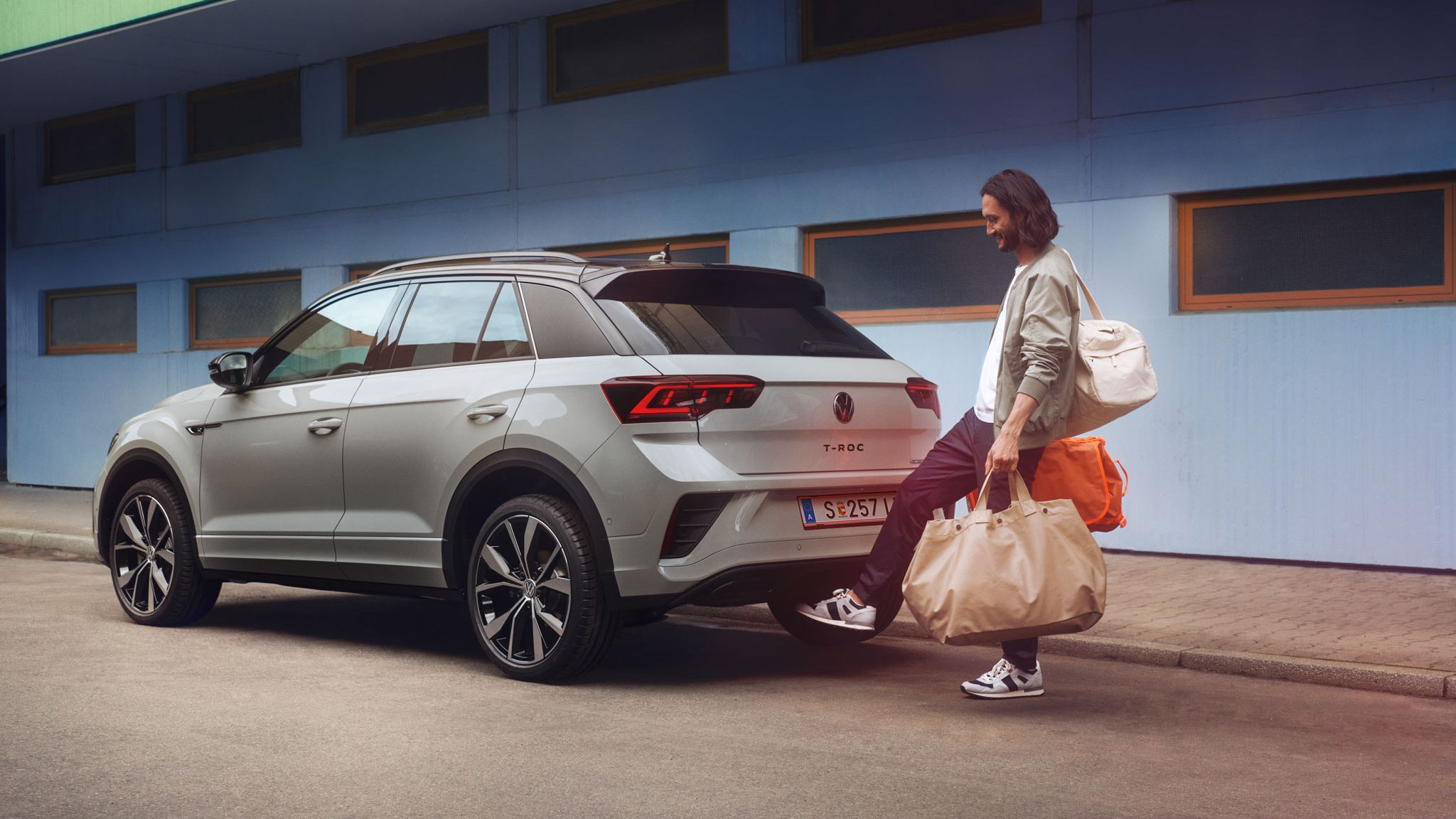 Ein Mann öffnet dank Keyless Access mit seinem Fuß den Kofferraum von VW T-Roc