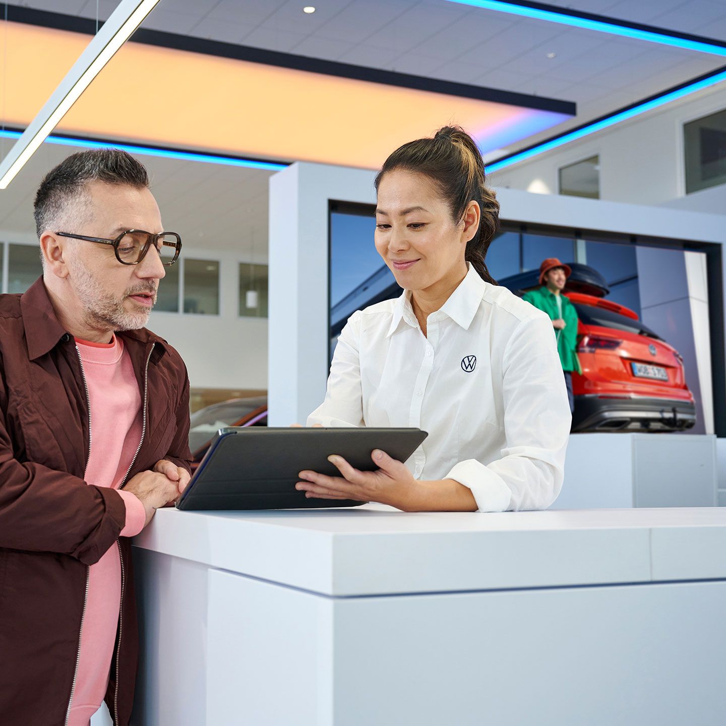 Eine Frau gibt einem Mann mithilfe eines Tablets Informationen.