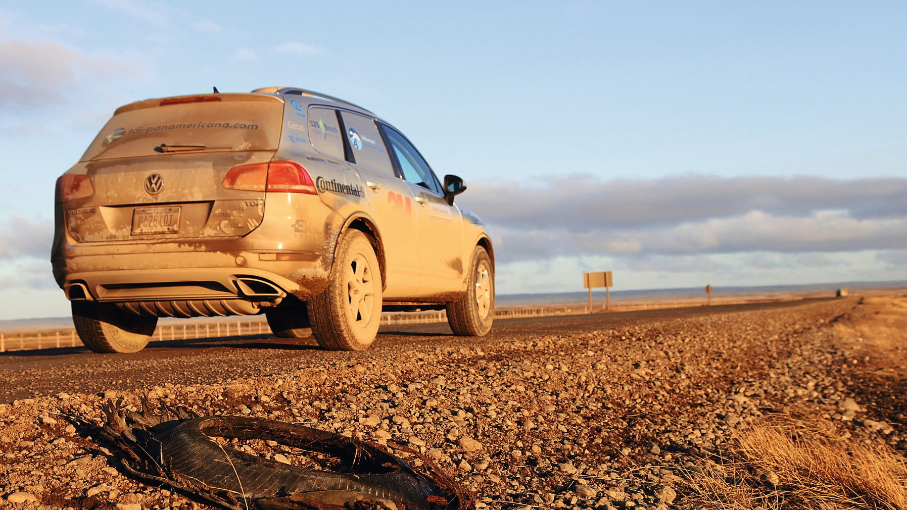Ein mit Dreck bedeckter Toureg steht auf einer Straße bei Sonnnuntergang.