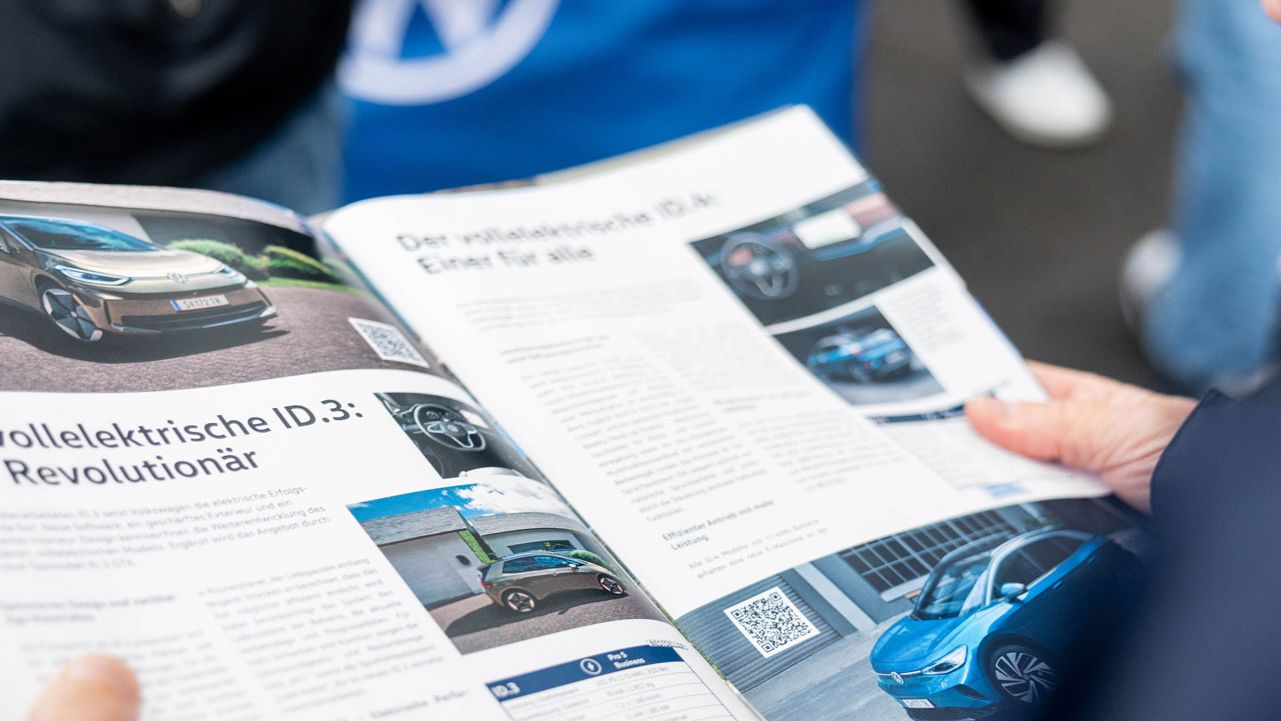 Ein Besucher der Wiener Elektro Tage 2025 ließt eine Ausgabe des VW Automagazins Flotte über elektrische Modelle.