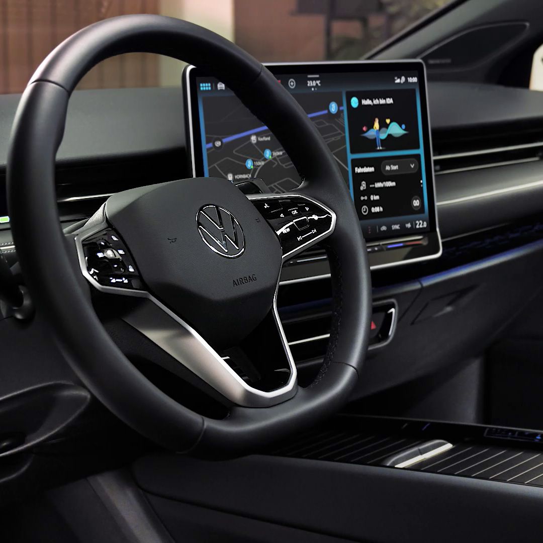 Das Bild zeigt das Innere eines Autos mit einem modernen, digitalen Armaturenbrett. Das Lenkrad trägt das Volkswagen-Logo. Auf dem Bildschirm ist eine Navigationskarte zu sehen.
