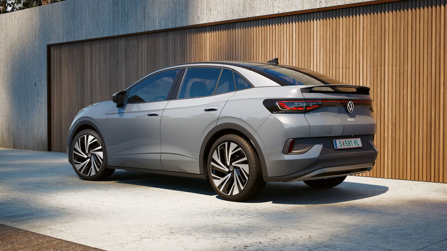 EIn VW ID.5 in Heckansicht steht seitlich vor einem modernen Haus mit Holzfassade.