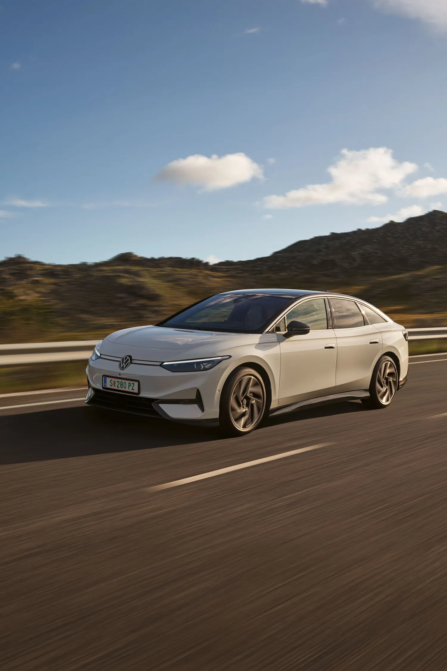VW ID.7 fährt auf einer Landstraße, Blick auf die aerodynamisch gestaltete Front.