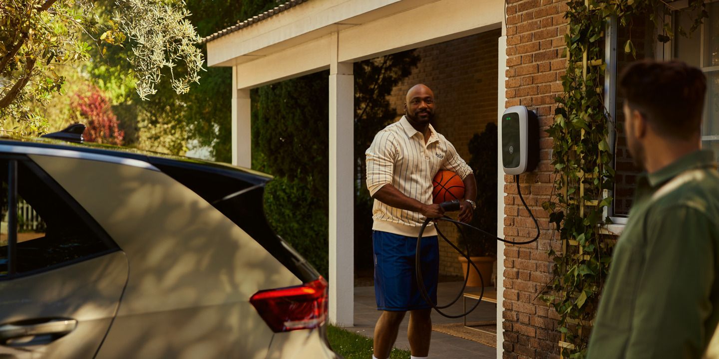 Ein Mann holt einen Ladestecker seiner Wallbox um seinen ID.3 zu laden. 