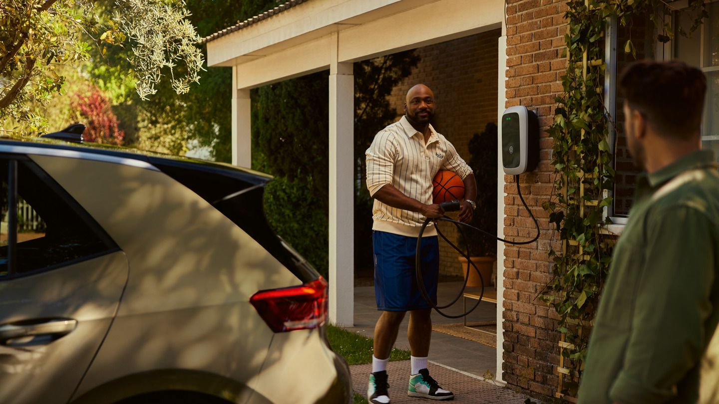 Ein Mann holt einen Ladestecker seiner Wallbox um seinen ID.3 zu laden. 