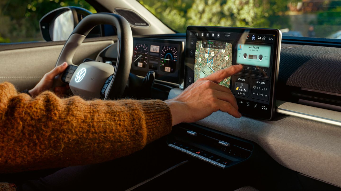 Detailansicht des Infotainment-Systems mit Naviagtionskarte im VW ID. Polo, welches von einer Hand bedient wird.