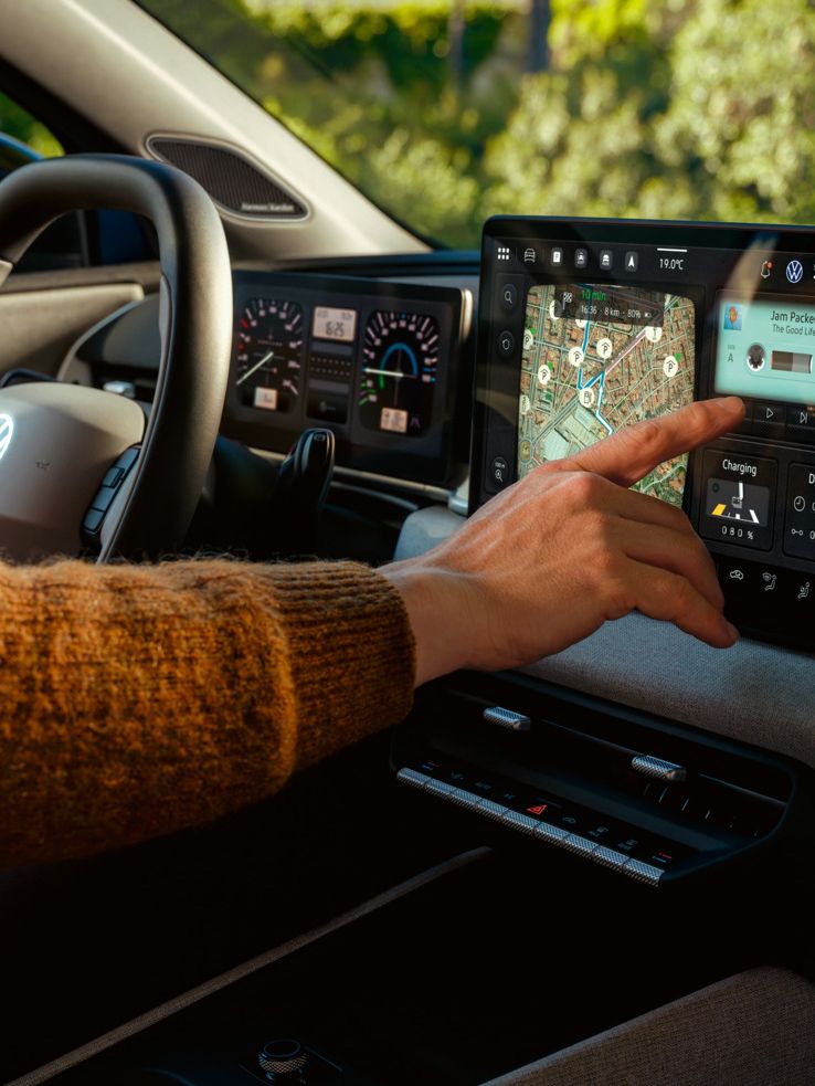 Detailansicht des Infotainment-Systems mit Naviagtionskarte im VW ID. Polo, welches von einer Hand bedient wird.