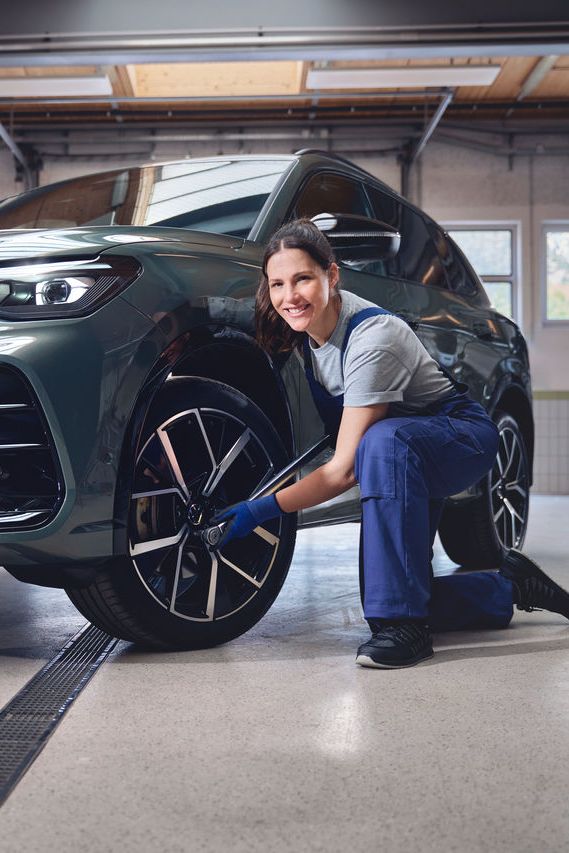 Eine Volkswagen Technikerin beim Reifenwechsel von einem Volkswagen Tiguan.