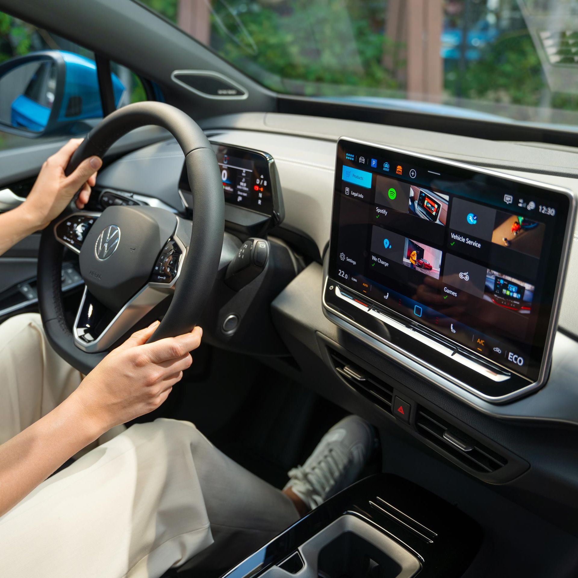 Lenkrad und Infotainment-System im VW ID.4, eine Frau sitzt auf dem Fahrersitz.