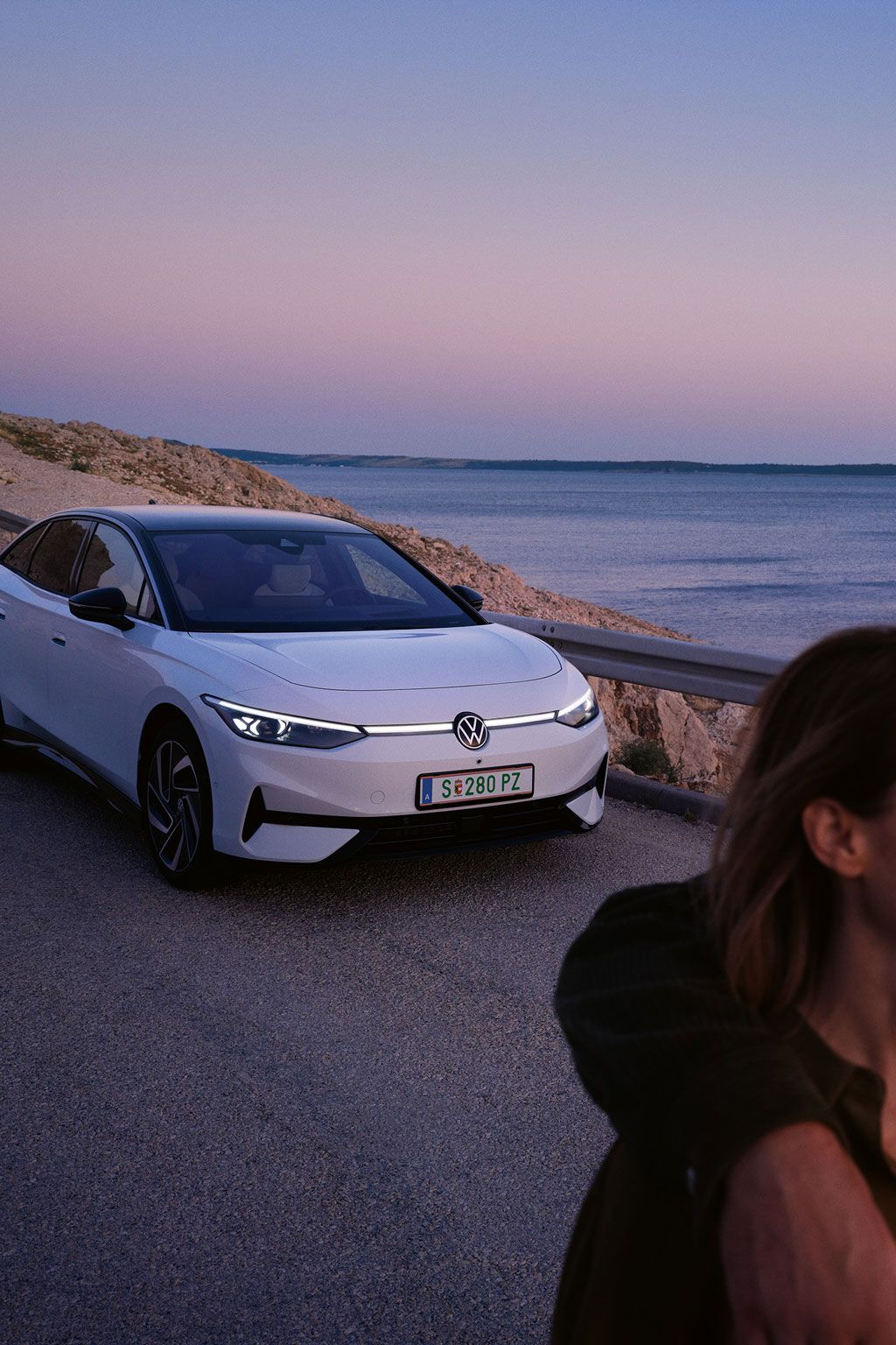 Ein Pärchen läuft am Meer entlang, im Hintergrund parkt ein ID.7 