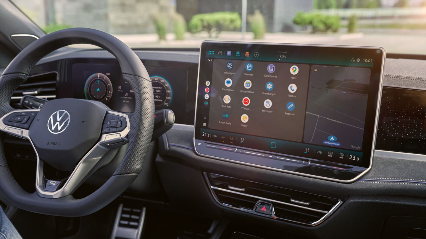 Detailansicht auf das Cockpit des VW Passast. Eine Person auf dem Fahrersitz hält ein Smartphone in der Hand.
