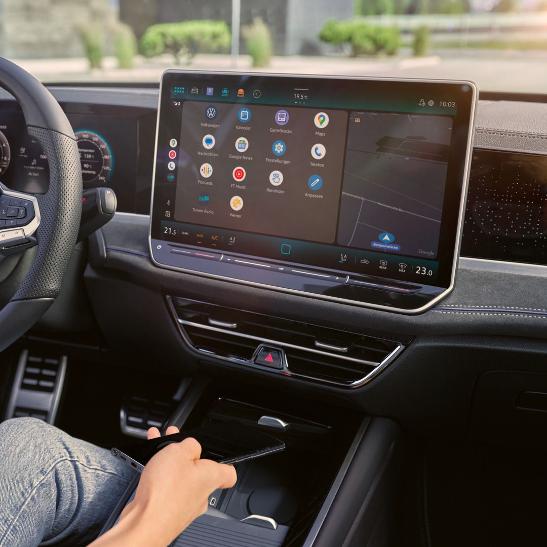 Detailansicht auf das Cockpit des VW Passast. Eine Person auf dem Fahrersitz hält ein Smartphone in der Hand.