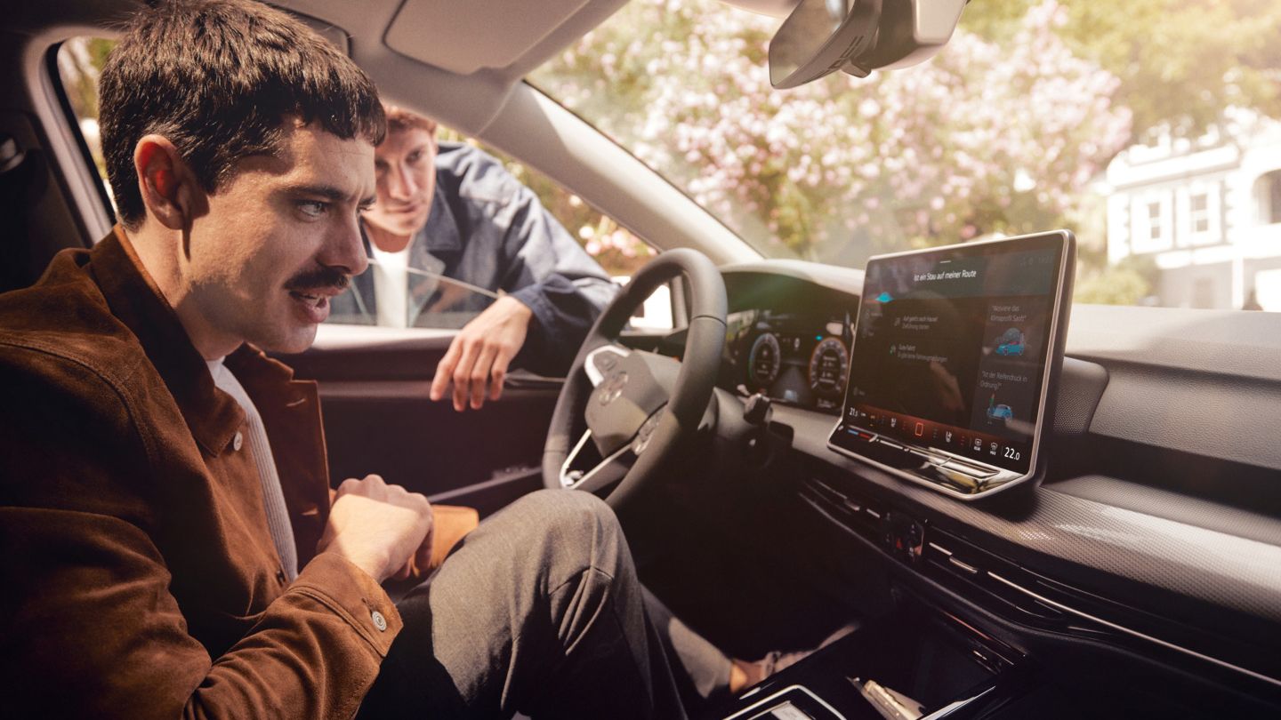 Zwei junge Männer nutzen den Sprachassistenten im VW Golf.